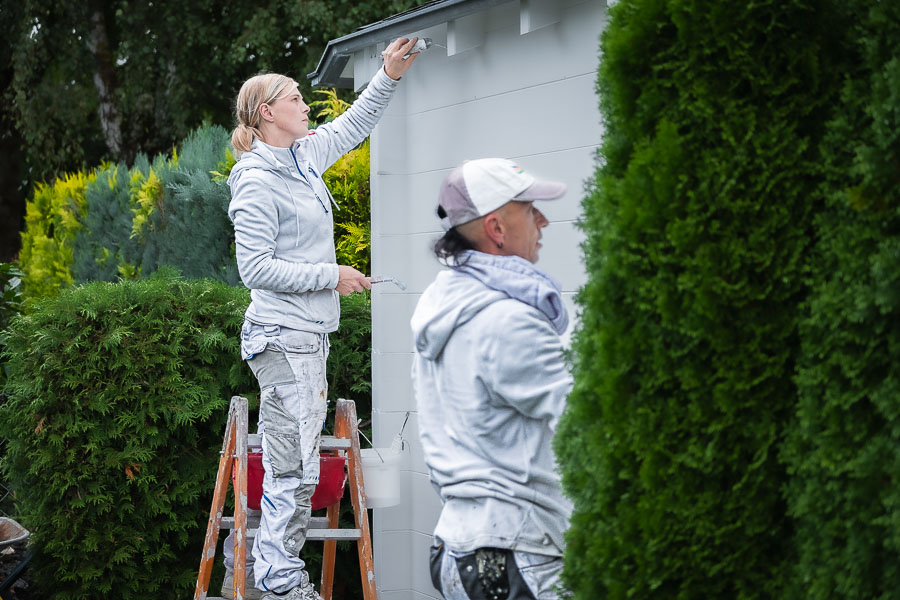Zwei Maler streichen ein Gartenhaus